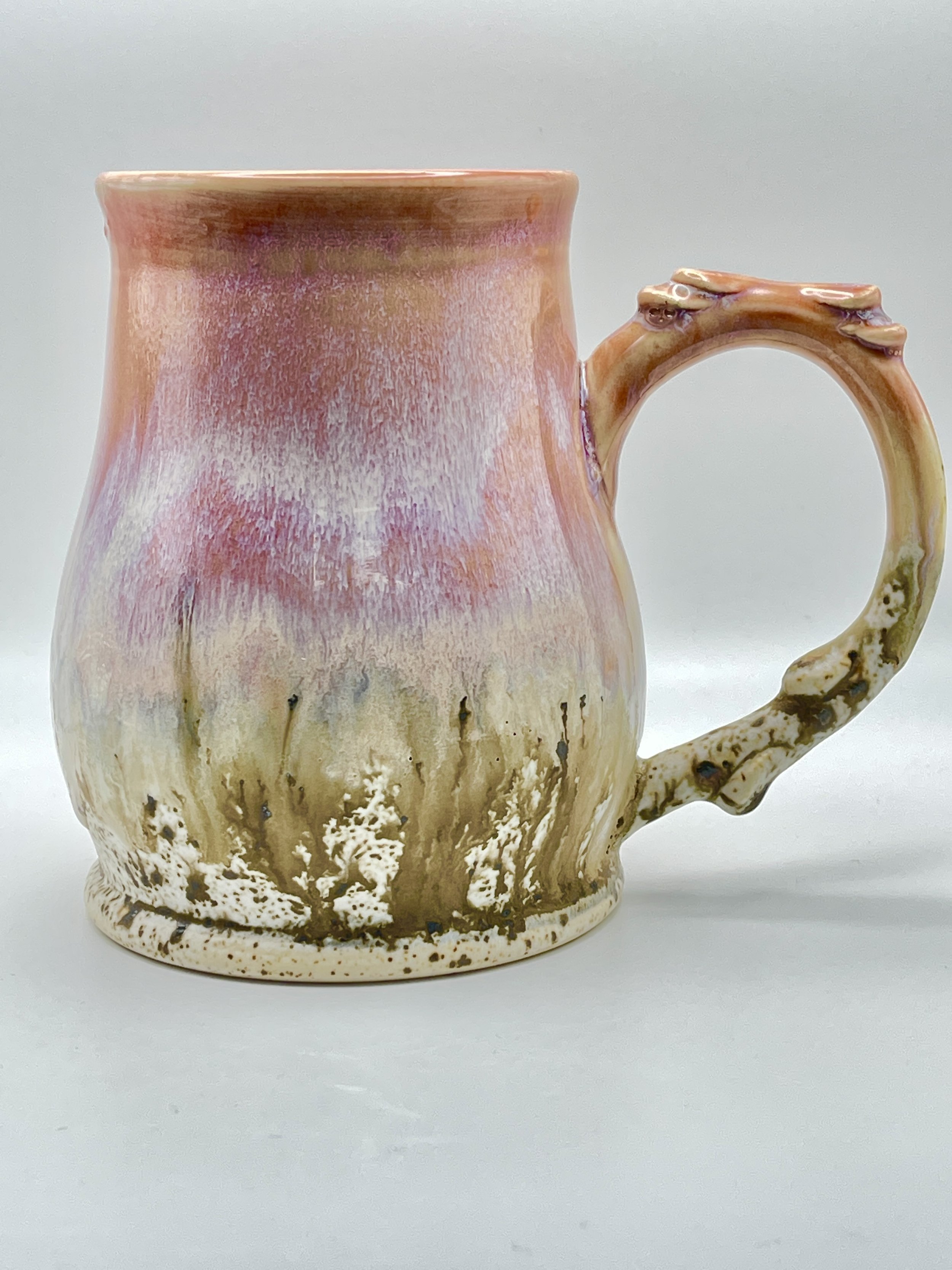 Pink tall mug with speckled bottom and pulled, embellished handle